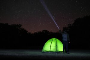 A lone camper observes the starlit sky near a glowing tent in Aksaray, Türkiye.