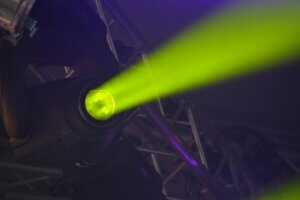 Close-up of a vivid neon spotlight emitting a green beam, part of modern stage lighting equipment.