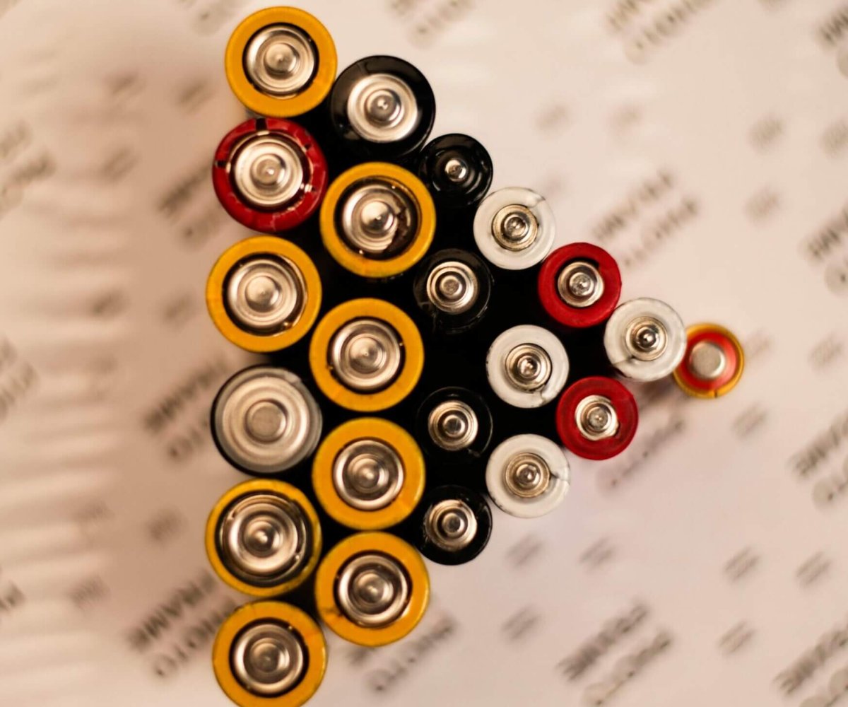 Top view of assorted batteries in an artistic arrangement on a printed surface.